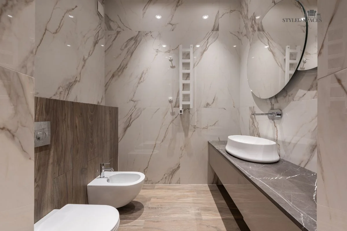 Dark stone bathroom warmed up with a plush rug and wood cabinetry