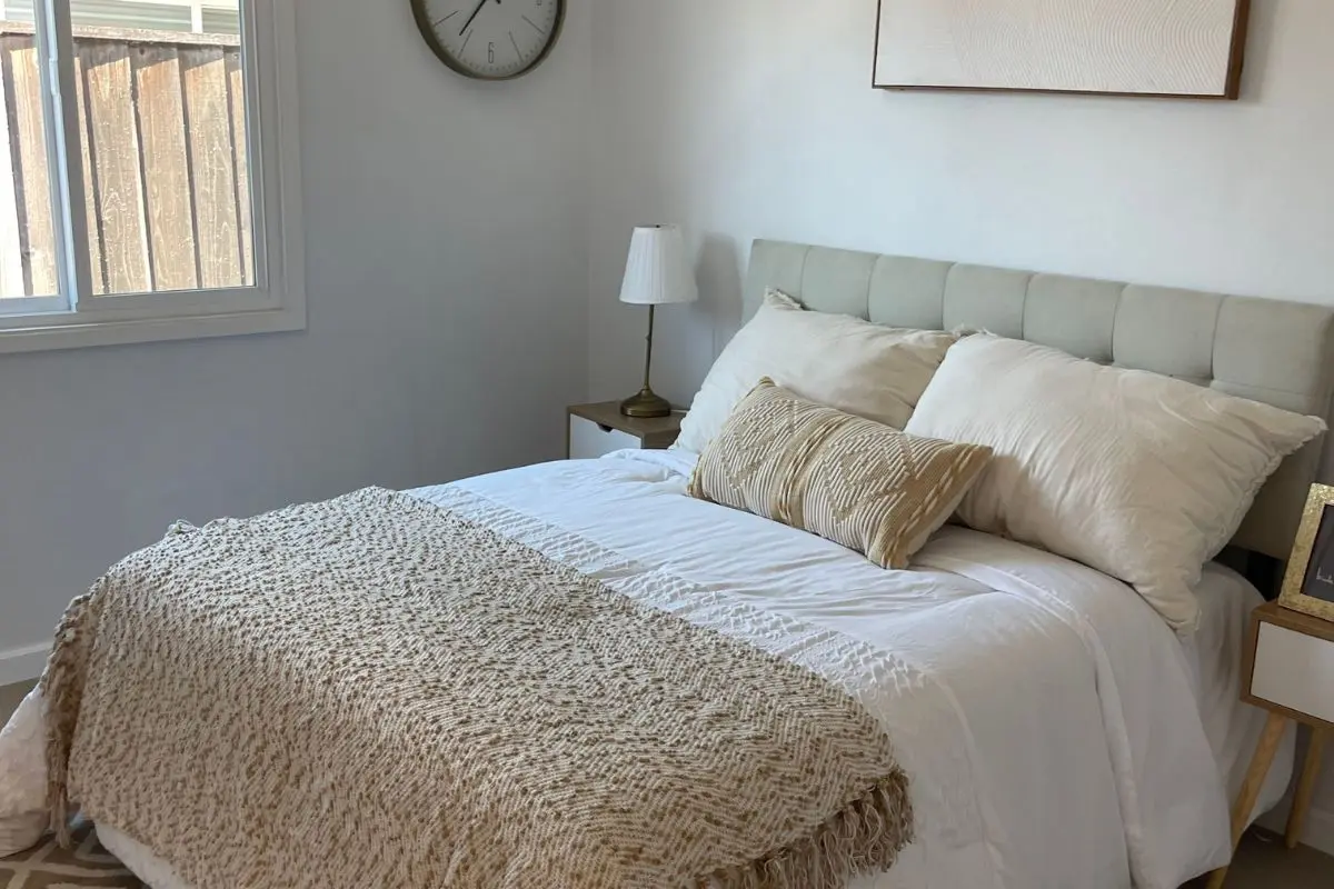 Bed layered with a linen duvet, knit throw, and mixed pillow textures