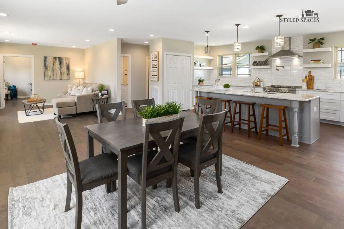 Dining table anchored in an open floor plan with a rug and pendant light