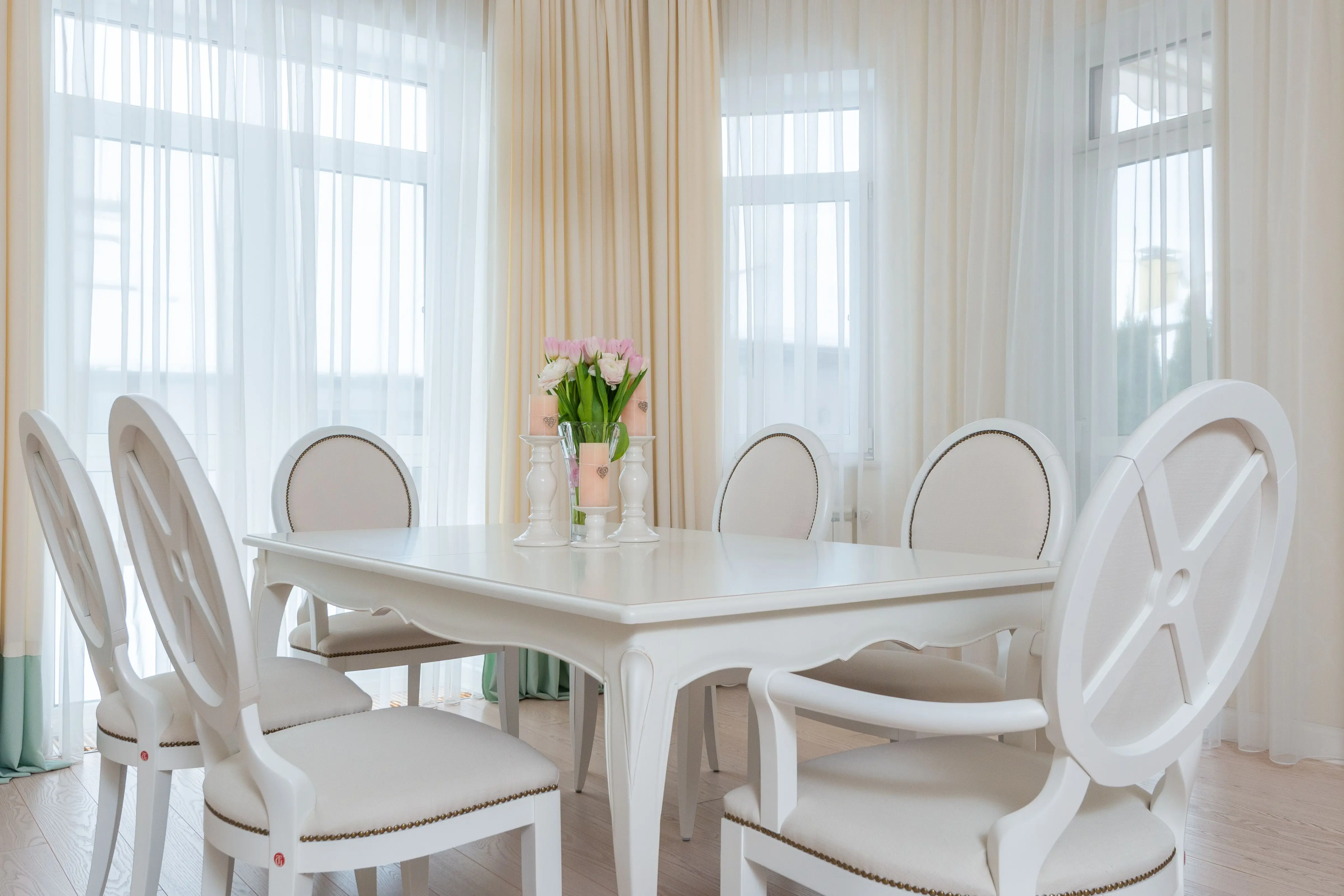 Dining room window layered with sheer and decorative drapery panels
